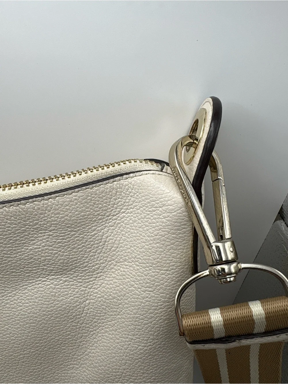Kate Spade New York cream leather crossbody bag featuring a striped webbing Stra